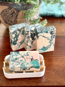 White, turquoise, black soap in a white compostable soap dish